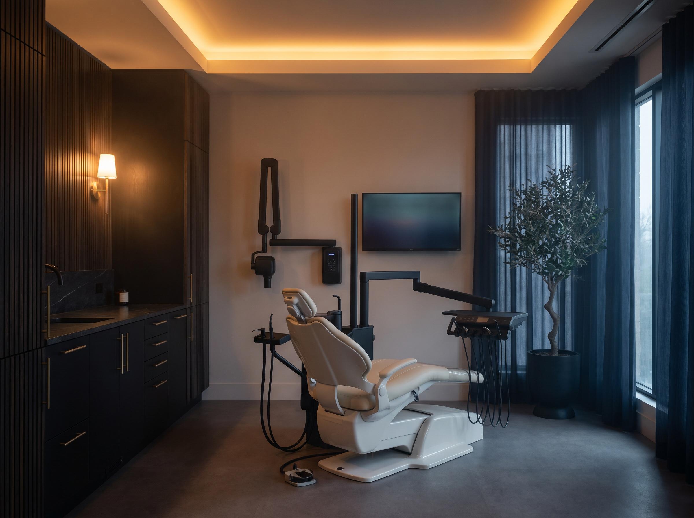 Consultorio con sillón dental marfil, mobiliario de madera oscura y luz cálida