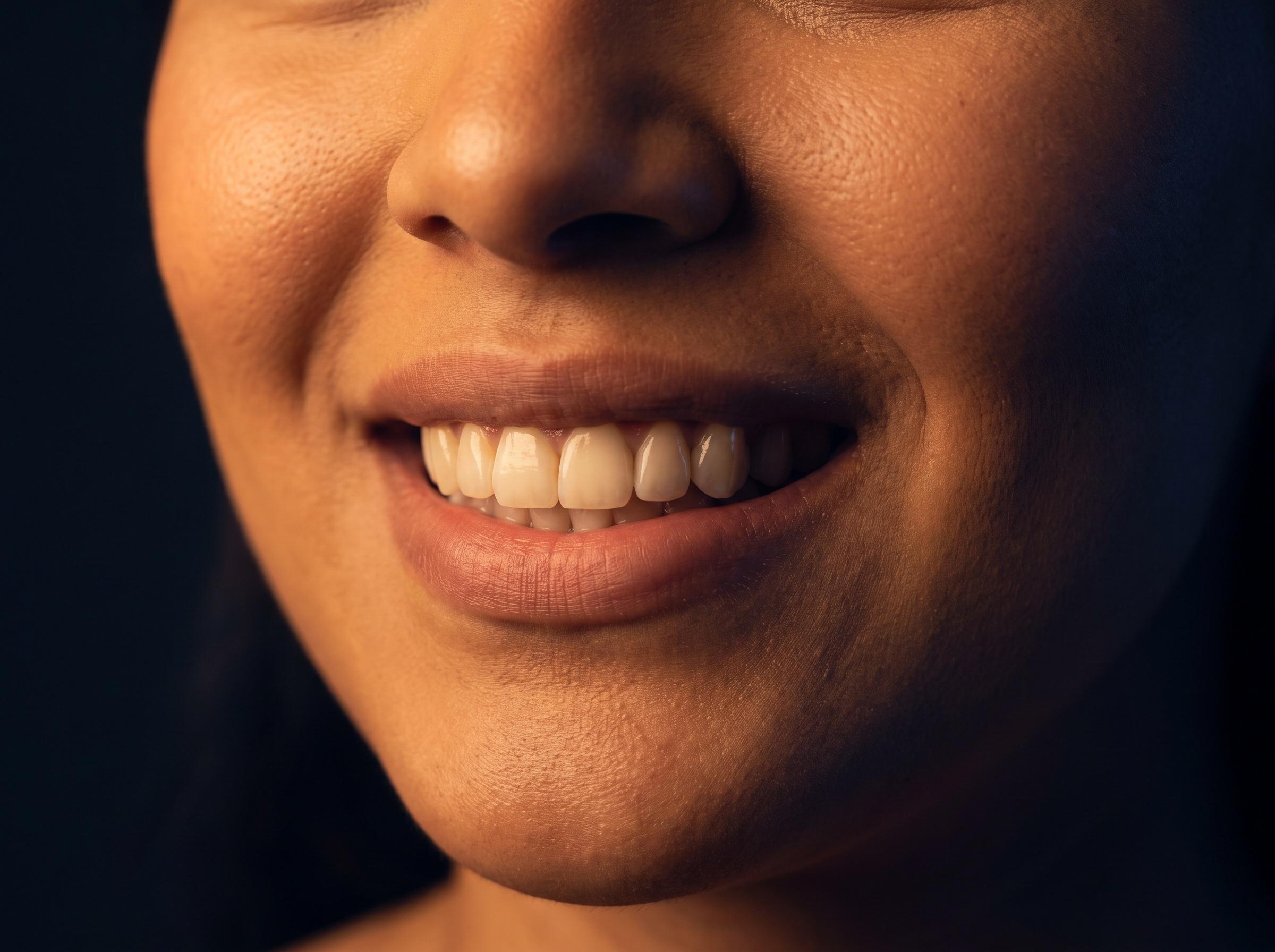 Sonrisa natural de una mujer iluminada con luz cálida lateral